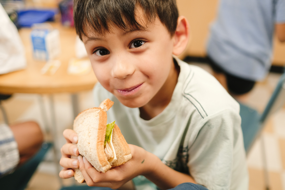 Smiling child enjoying school lunch